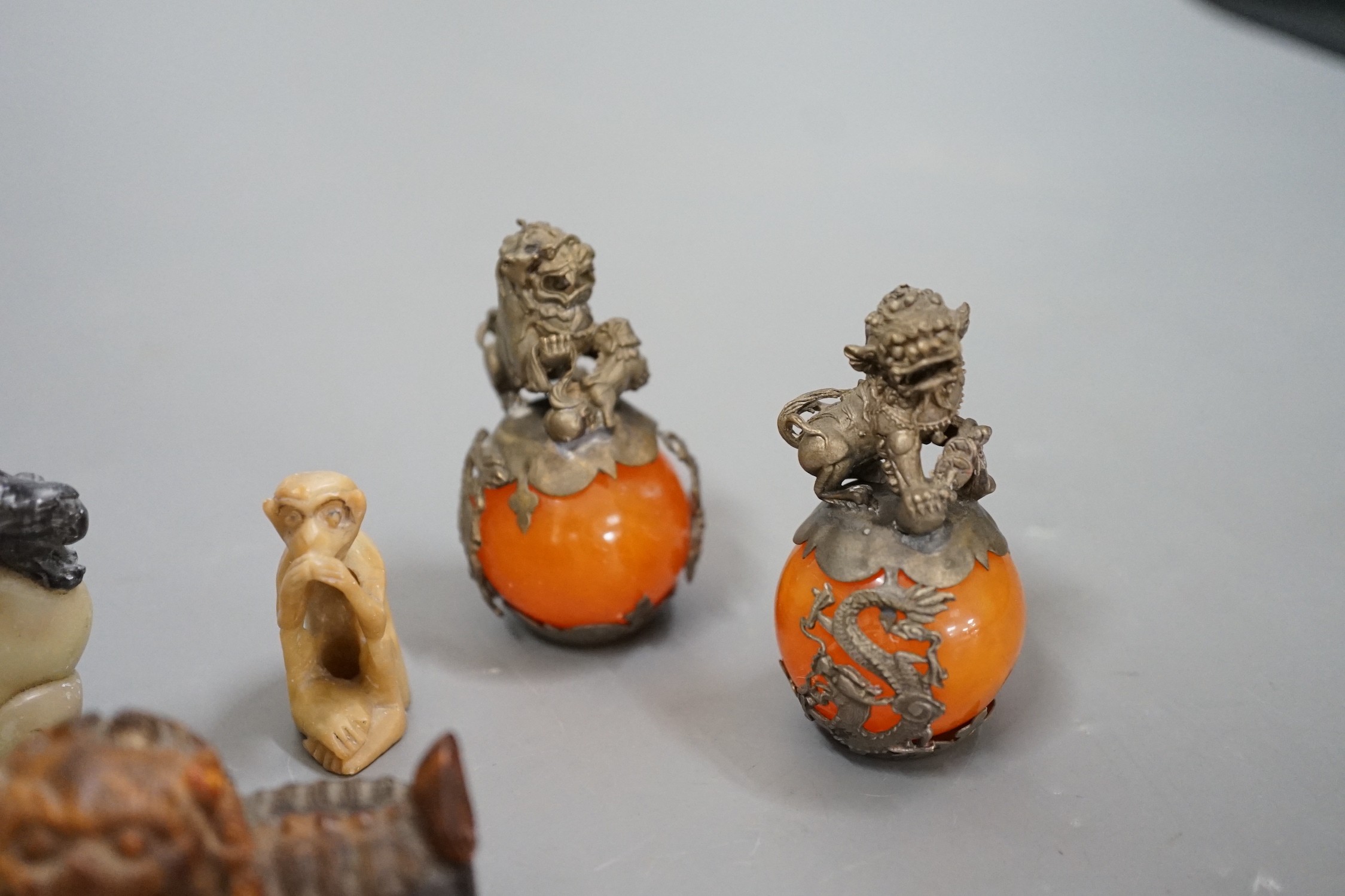 Two carved horn Buddhistic lions, four soapstone carvings and a pair of Chinese nickel and amber-glass ornaments, horn lions 5cm wide